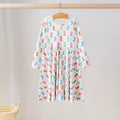 White long-sleeve dress with colorful cowboy boots and stars, a gathered skirt, and a round neckline, hanging on a wooden hanger.